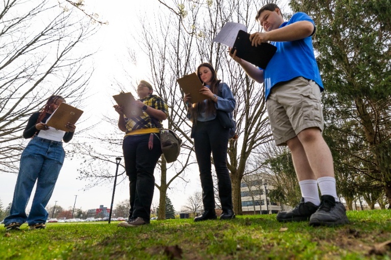 Students stand outside with clipboards for a CO2 measurement and tree identification activity in April 2024 on campus at IU South Bend.